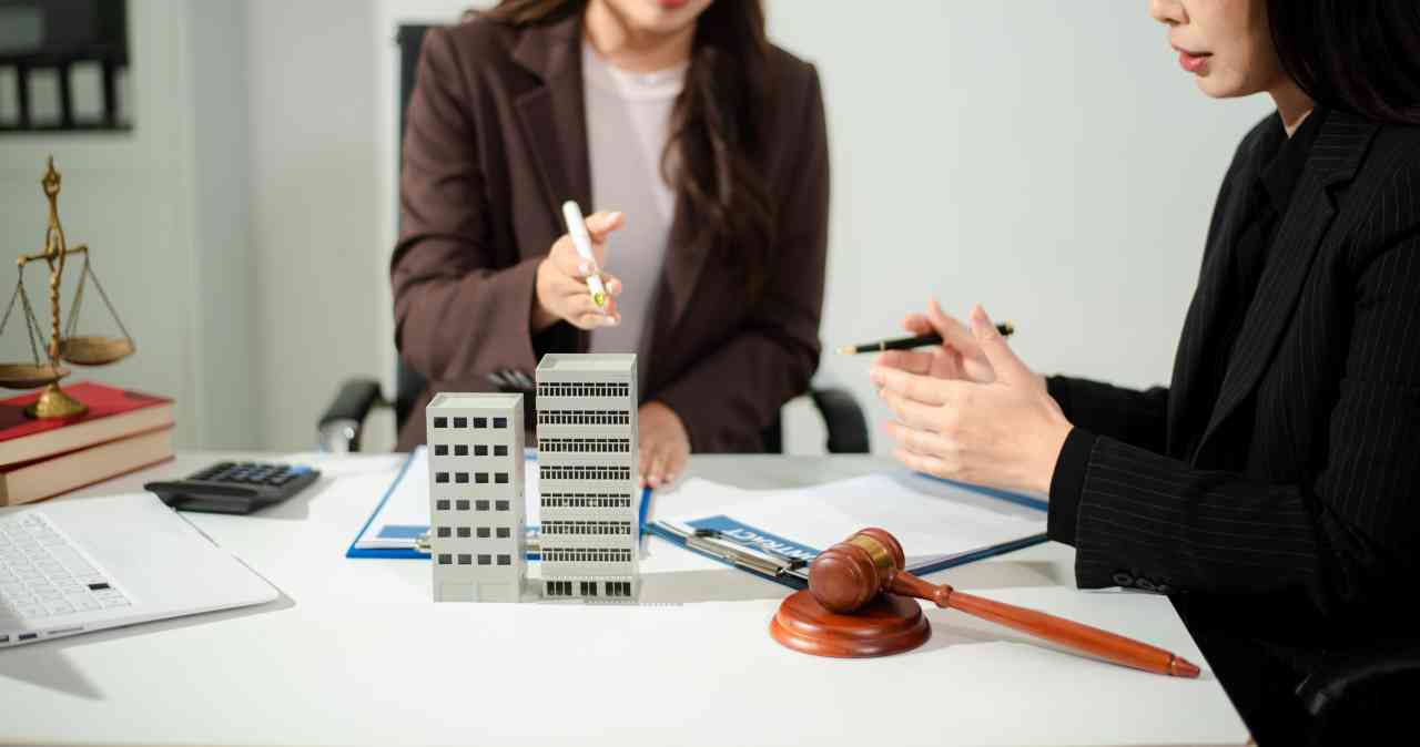Real estate lawyer reviewing property contract with building model and gavel, concept of investment agreement, mortgage consultation, legal compliance and business transaction.