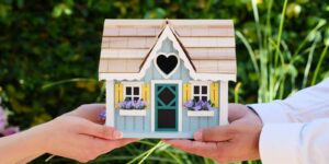 close-up of hands holding a detailed miniature house model, symbolizing goals of homeownership
