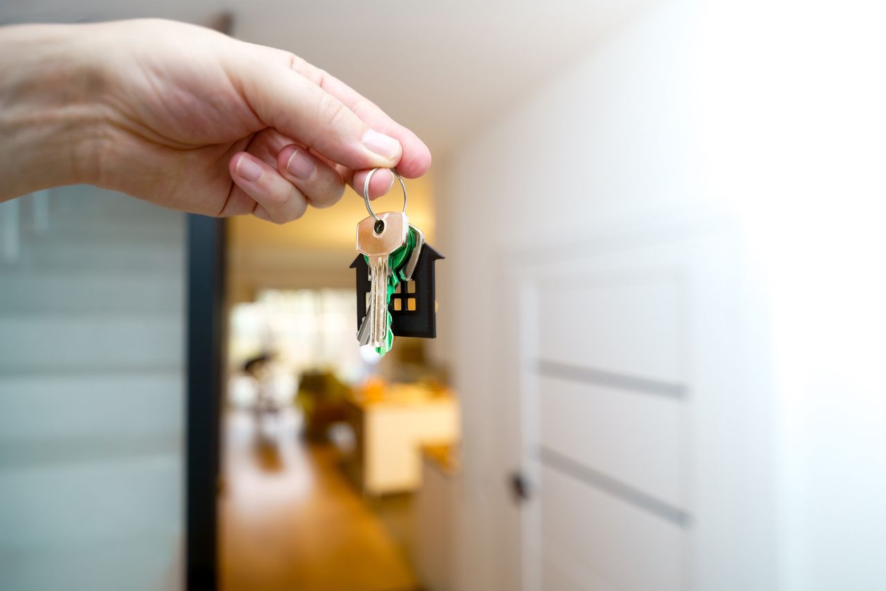 hand holding house keys inside a modern apartment, symbolizing new property ownership or rental