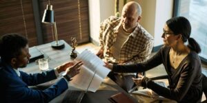 black male lawyer reviewing documents with middle aged couple during divorce consultation in office