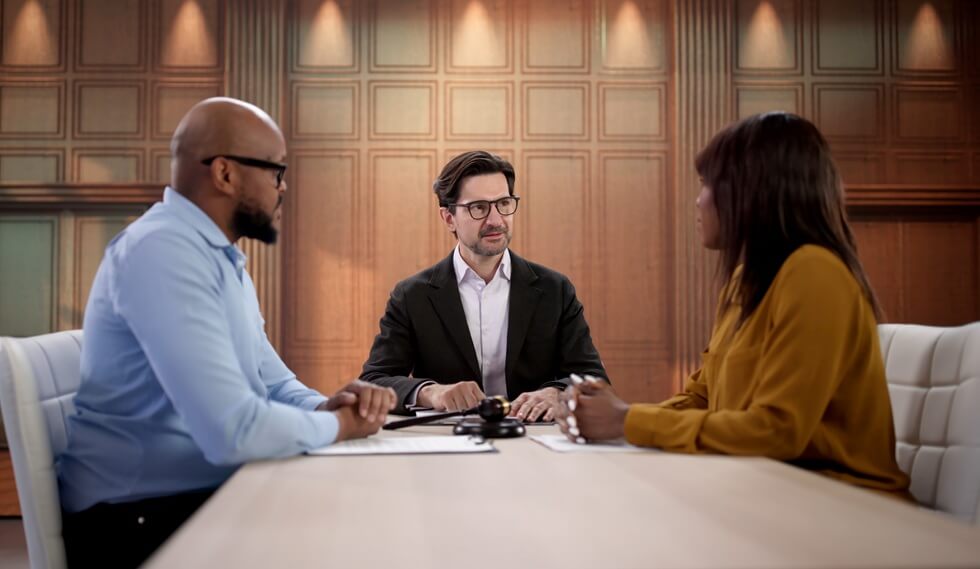 friendly divorce attorney greets african couple during family mediation
