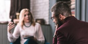 bearded man wearing glasses feeling concerned visiting therapist