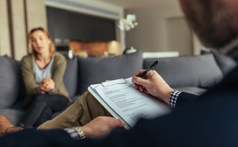 psychologist writing notes during a therapy session with patient